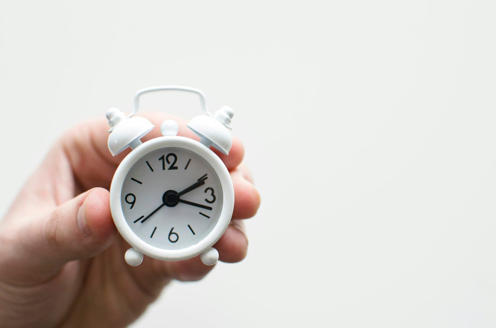 A small alarm clock held in one hand
