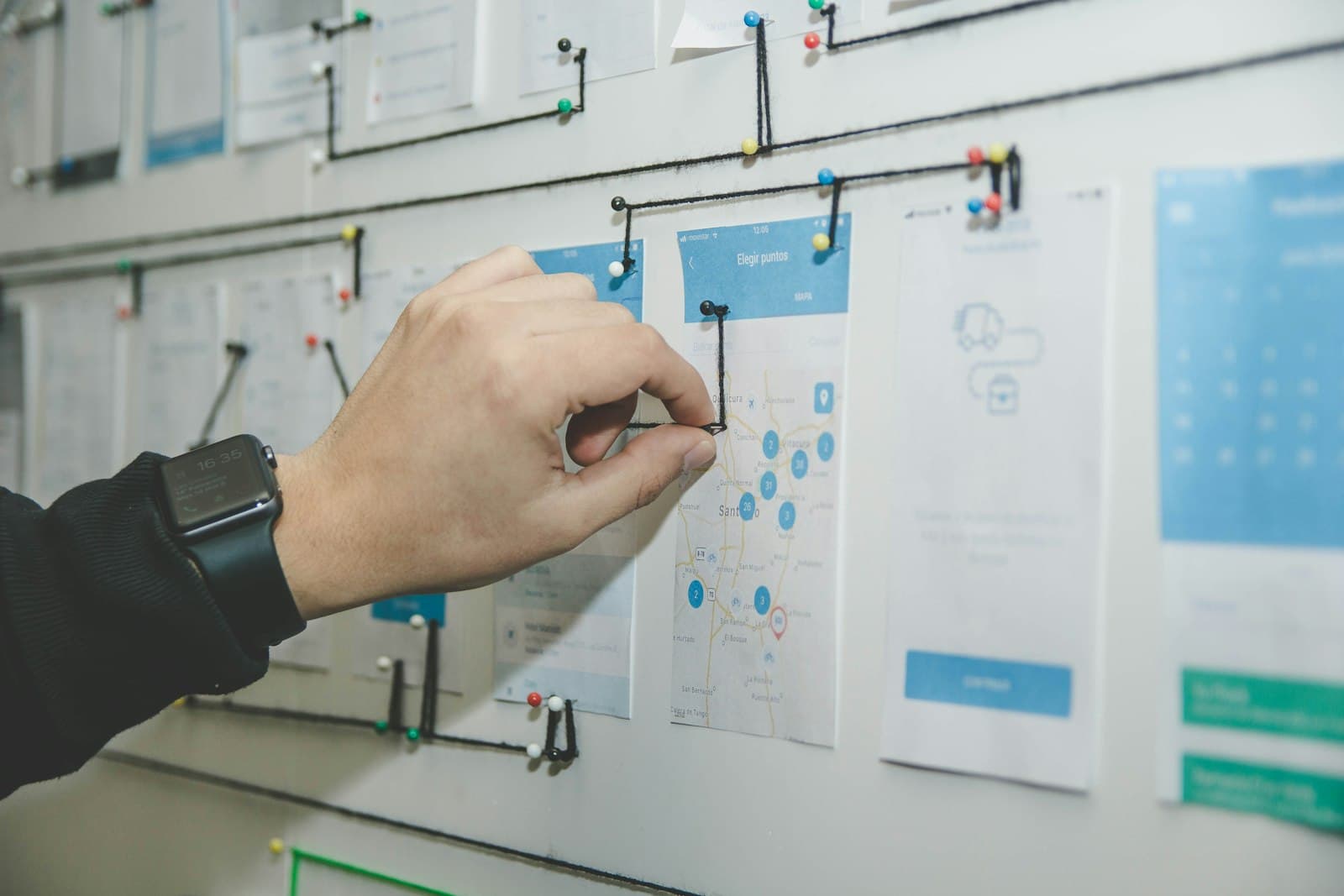 A hand pinning workflow cards to a wall