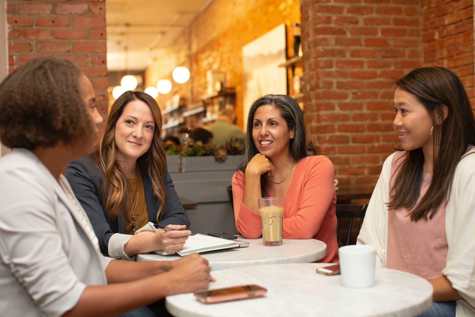 Four people talking around a small table with notebooks