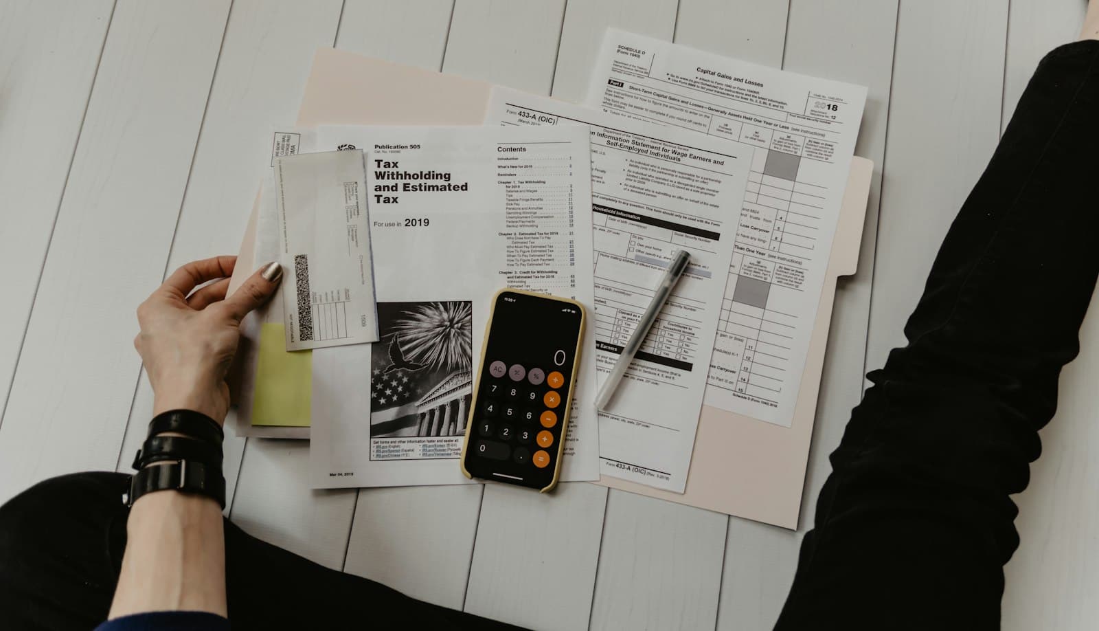 Tax forms, a pen, and a phone calculator spread on a desk