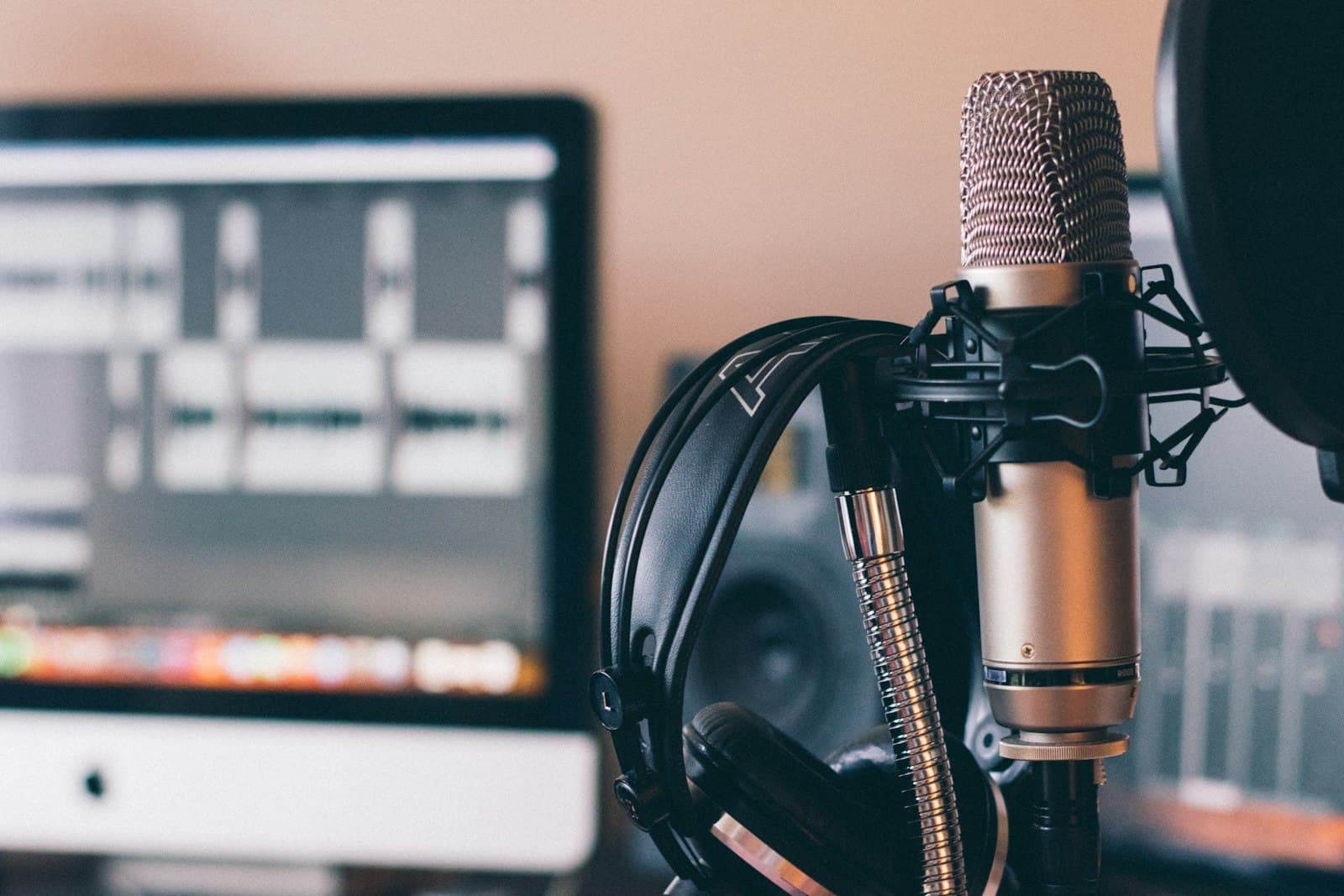 A studio microphone, headphones, and a waveform on a screen
