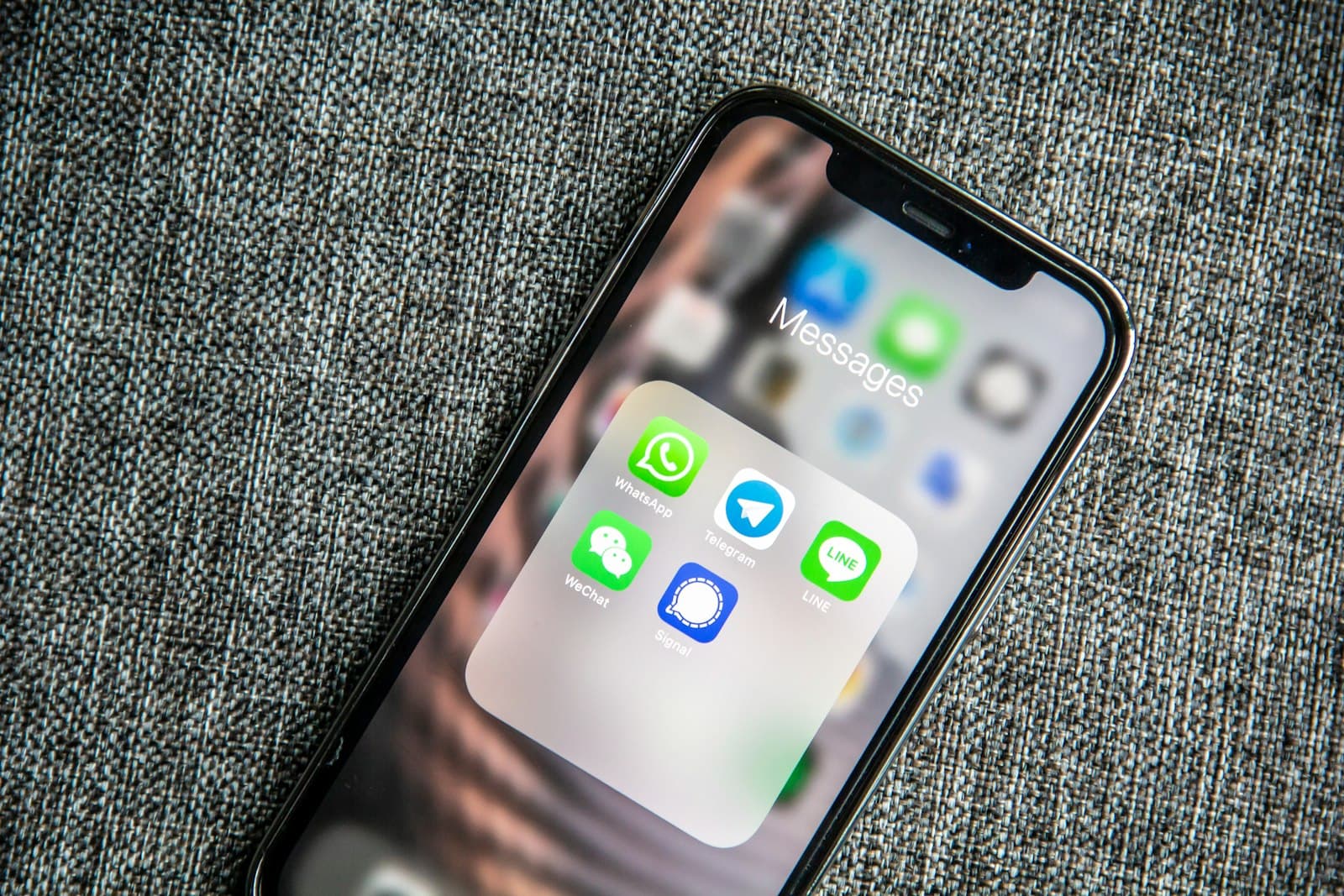 A phone screen with the WhatsApp icon in a messages folder